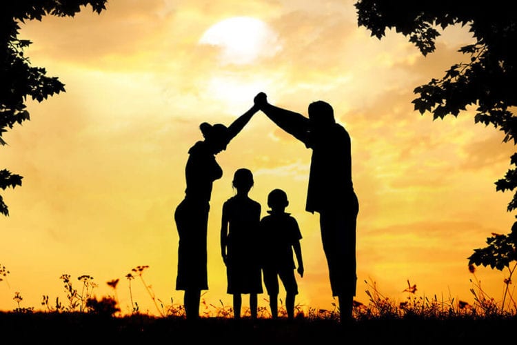 photo of an Alberta family, silhouette of a house with the children covered by the parents